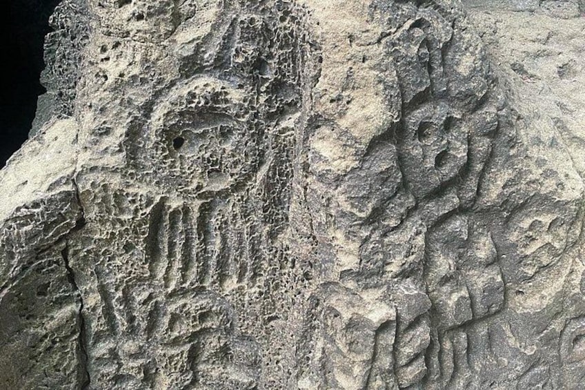 A rock formation with carved figures and patterns. 5