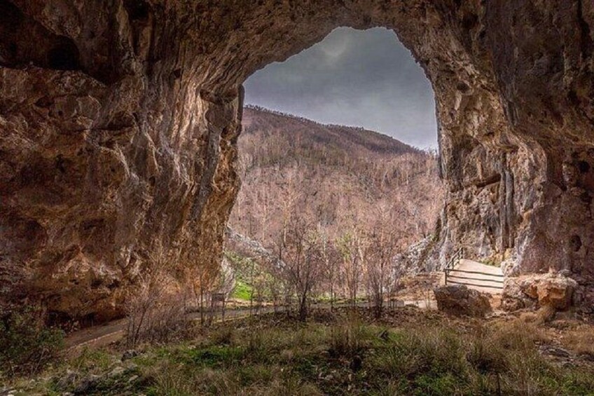Una formación natural de arco de roca con vistas a una ladera boscosa. 1