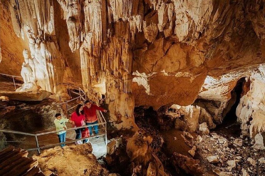 En grotta med stalaktiter och stalagmiter, ett metallräcke och människor som betraktar formationerna. 3
