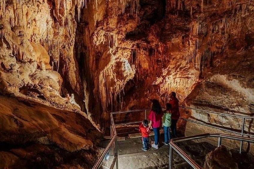 En grotta med stalaktiter och stalagmiter, ett metallräcke och människor som står på en plattform. 2