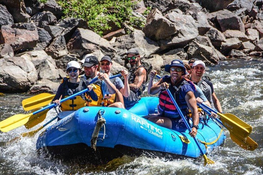 A group of people in a blue raft navigating a river. 2