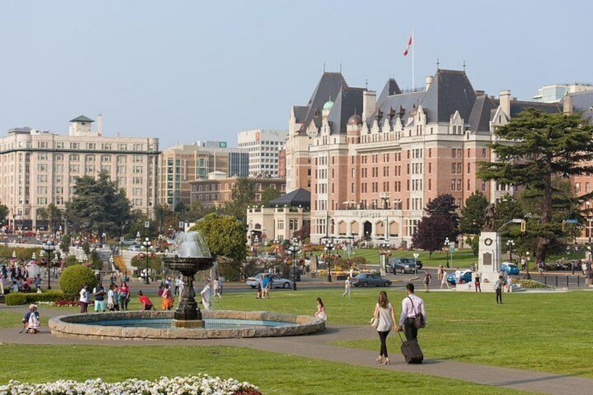 A public square with a fountain, people walking, and historic buildings in the background. 2