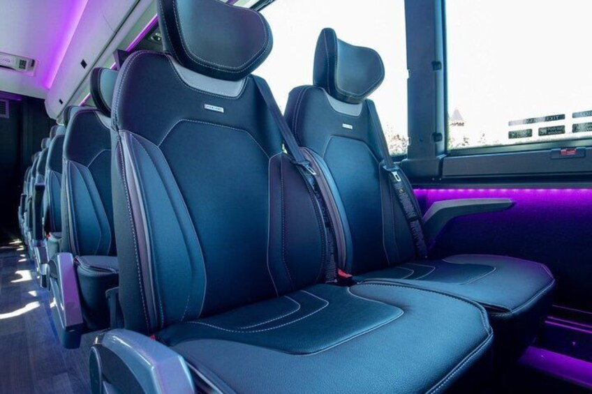 A row of black leather seats with a purple ambient light. 3