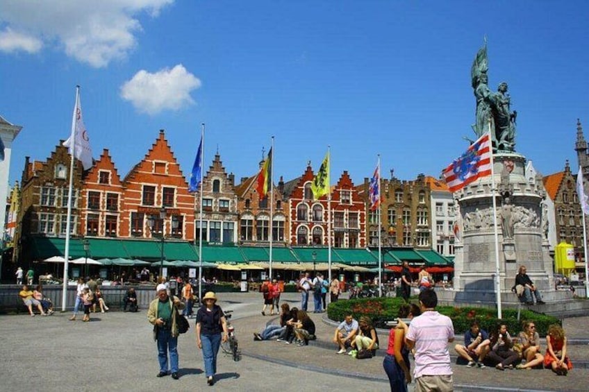 En offentlig plads med historiske bygninger, flag og en statue. 2