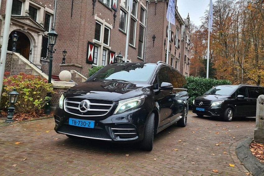 En sort Mercedes-Benz SUV holder parkeret på en brostensbelagt sti foran en historisk bygning med et rødt og hvidt flag. 3