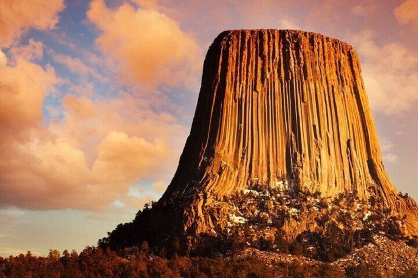 A large, steep-sided rock formation with a flat top, surrounded by a forested area. 3