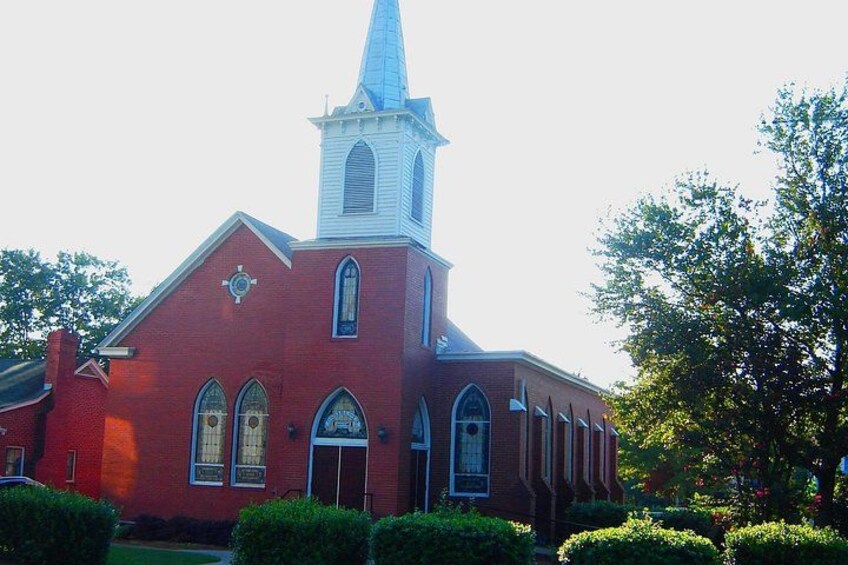 A red brick church with a steeple and arched windows. 3