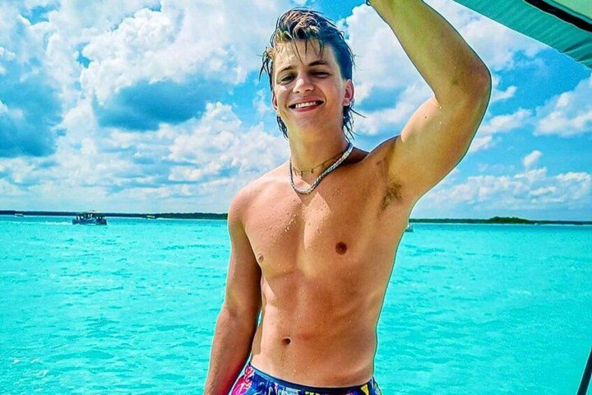 A person standing on a boat with turquoise water and a clear sky in the background. 2