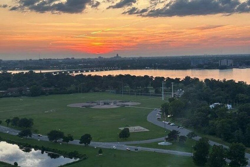 A baseball field with a stadium in the background, a river, and a sunset. 2