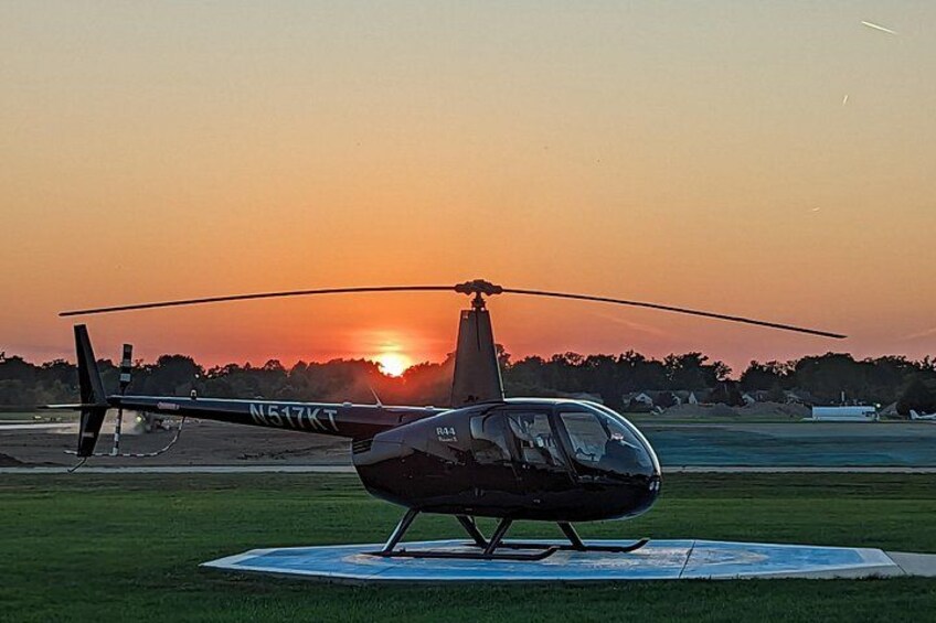 A helicopter on a landing pad with a sunset in the background. 3