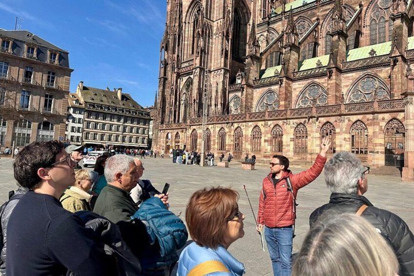 A historic cathedral with intricate architecture, a crowd of people, and a clear blue sky. 5