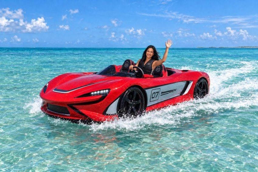 Ein roter Sportwagen fährt durch klares türkisblaues Wasser. 2