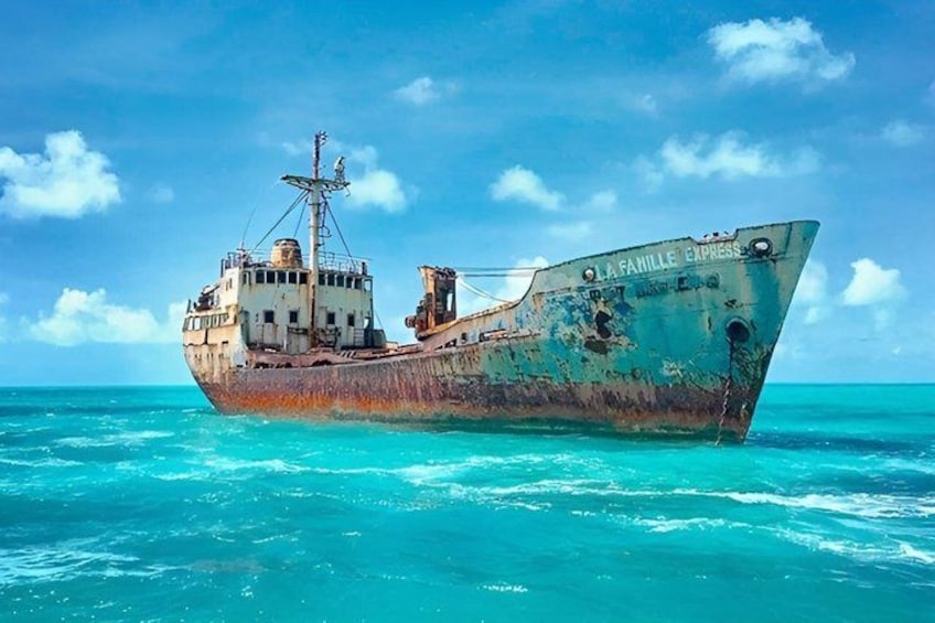 Ein verrostetes Schiff namens 'La Famille Express' auf türkisfarbenem Meer. 5