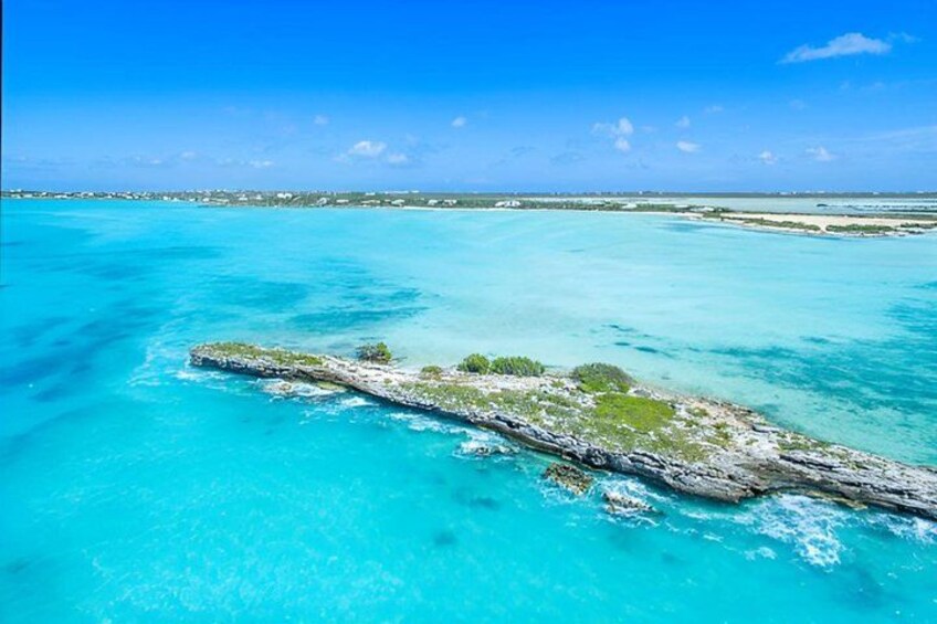 Ein türkisfarbenes Meer mit einer kleinen Insel, bewachsen mit grüner Vegetation. 4