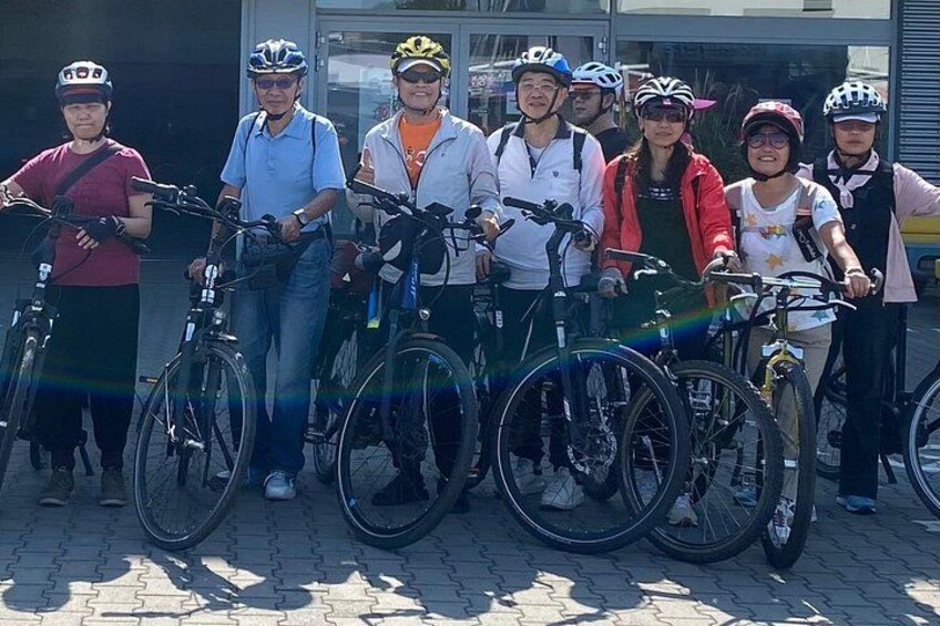 A group of people with bicycles standing on a paved surface. 4
