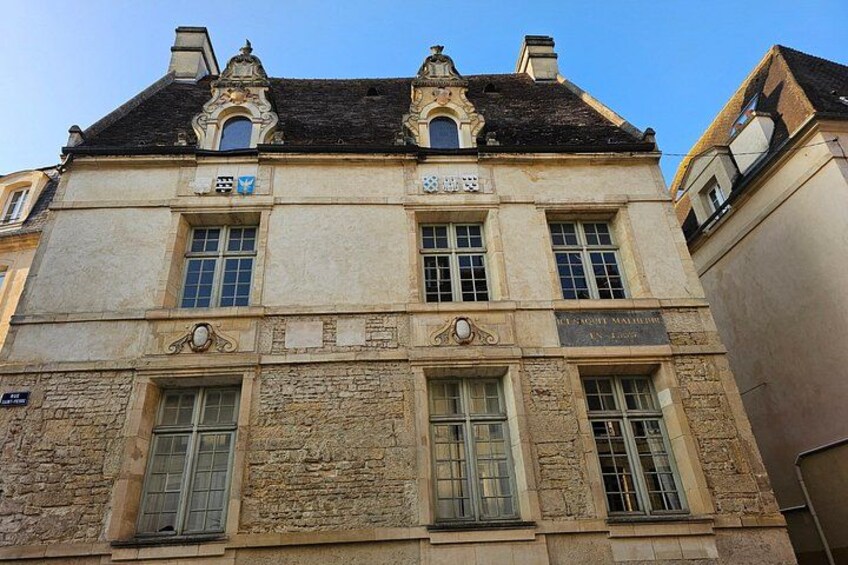 A historic building with ornate architectural details, including a clock and decorative window frames. 5