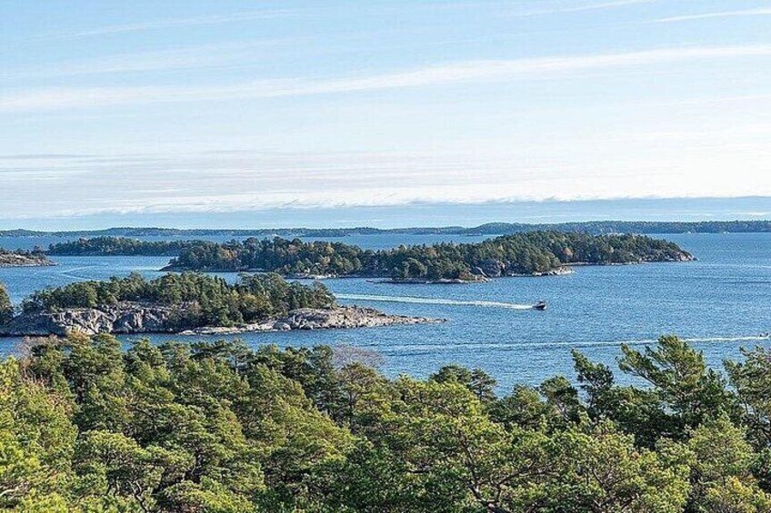 A coastal landscape with dense green trees, calm blue waters, and distant landforms. 3