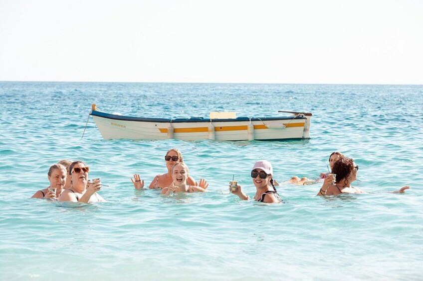 A group of people swimming in the ocean with a boat in the background. 3