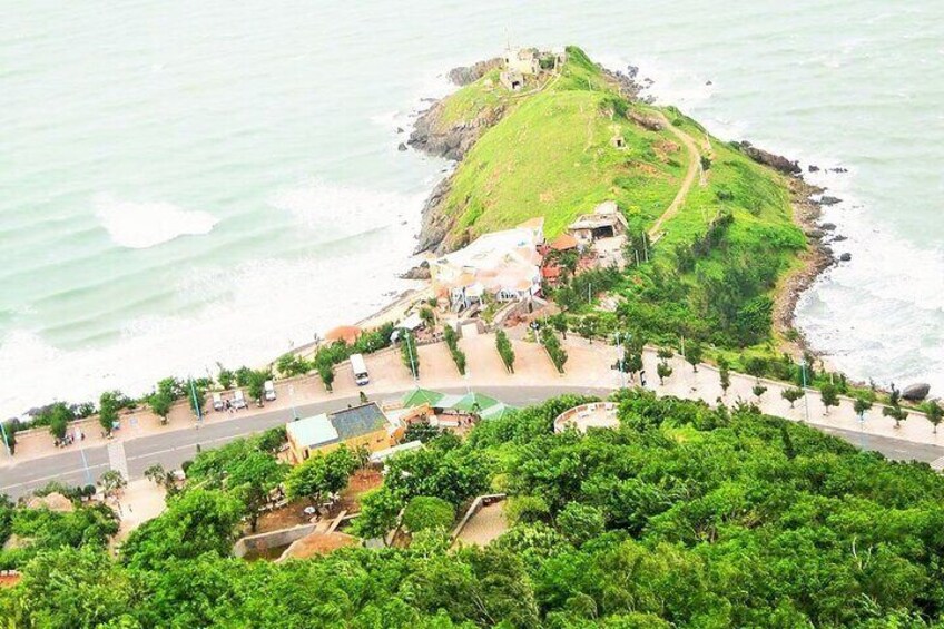 A coastal town with a prominent hill, a road, and a beach. 4