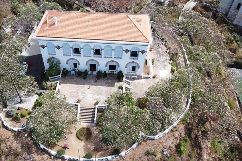 A white building with a tiled roof, surrounded by trees and a circular pathway. 3
