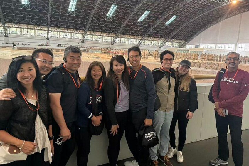 A group of people posing in an indoor exhibition space with a large open area in the background. 1