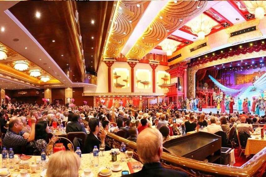 A crowded theater with ornate decorations and a stage. 2