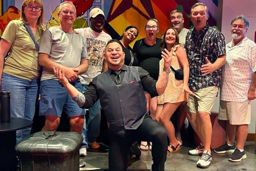 Un grupo de personas posando para una foto en un espacio interior con coloridas decoraciones geométricas en la pared. 1