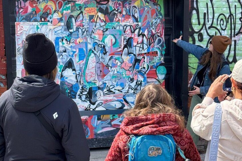 A group of people observing a colorful graffiti wall. 2