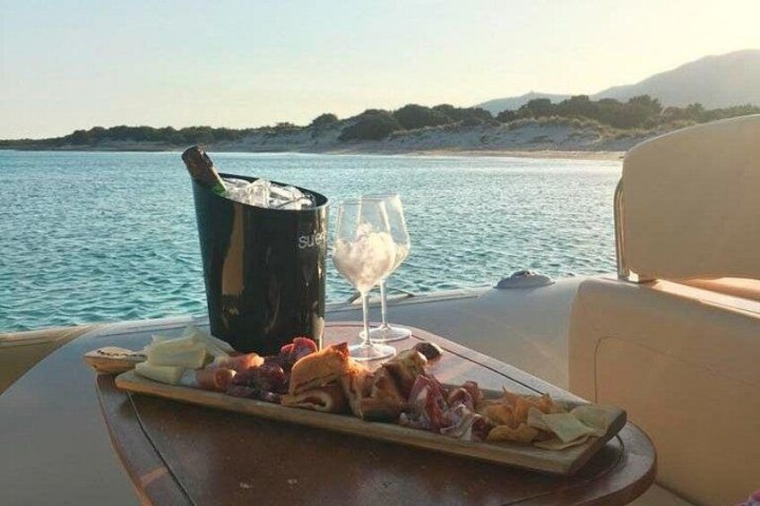 A boat with a table set with food and drinks, a bottle of champagne, and a glass of white wine. 3