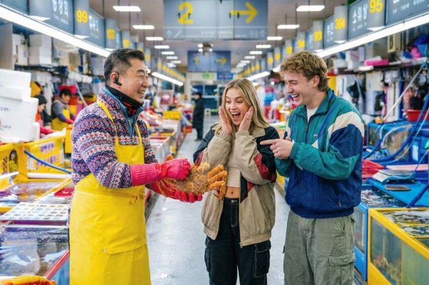 En marknadsplats med folk som handlar och en försäljare som håller upp en produkt. 2