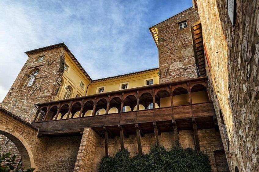 A historic building with a stone tower, arched balconies, and a wooden walkway. 4