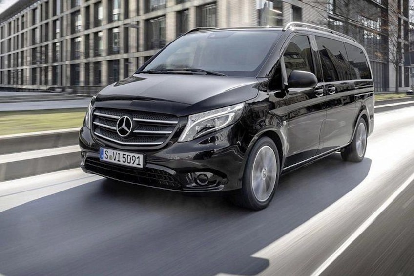 A black Mercedes-Benz SUV driving on a road with a modern building in the background. 2