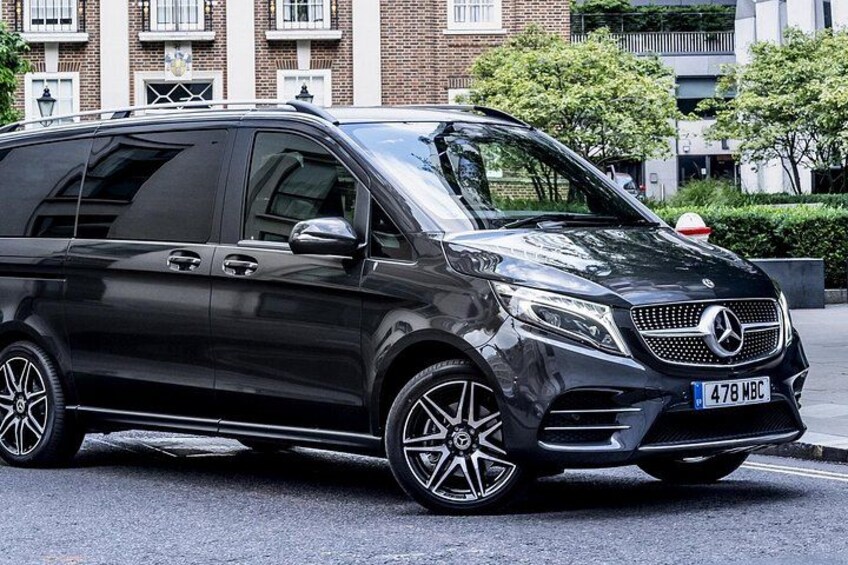 A black Mercedes-Benz SUV parked on a street with buildings and trees in the background. 3