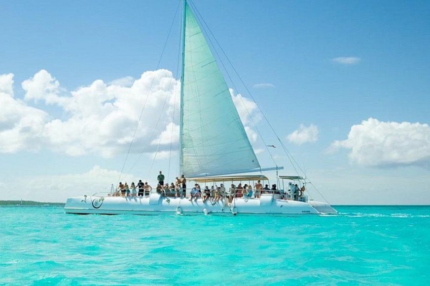 A sailboat with people on board, floating on turquoise water. 3