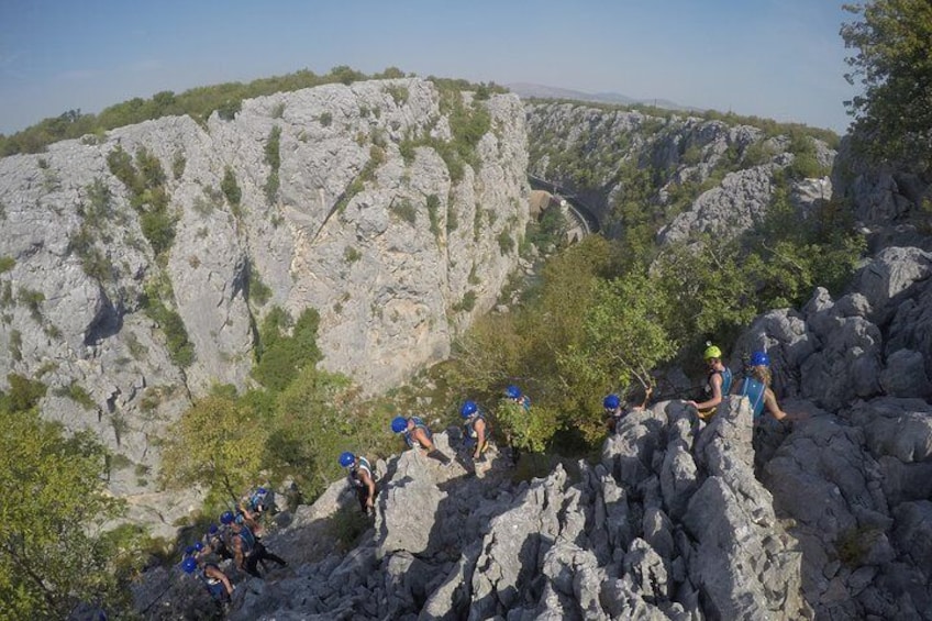 Un groupe de personnes fait de la randonnée sur un terrain rocheux, avec un paysage montagneux en arrière-plan. 3