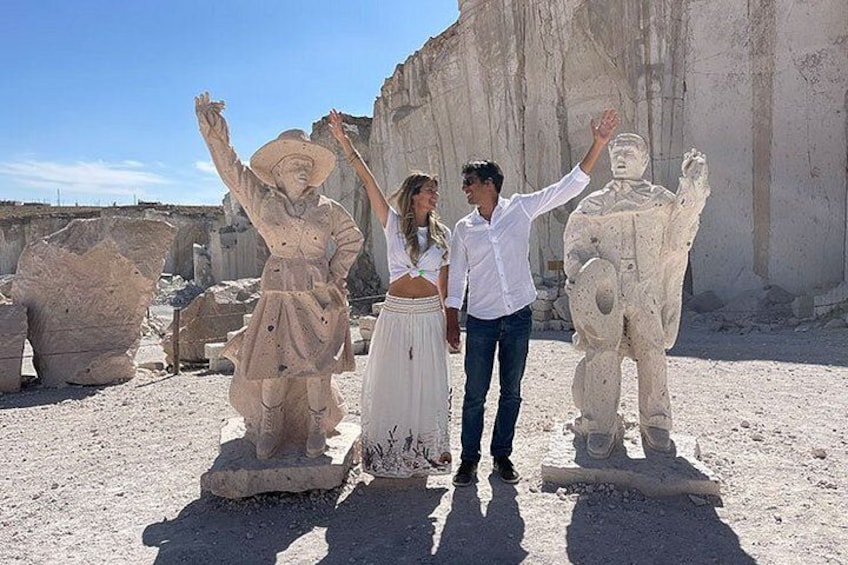 Tre persone in piedi di fronte a imponenti statue di pietra in un paesaggio desertico. 3