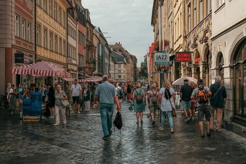Une rue animée, avec des piétons, des étals de marché et des bâtiments. 5