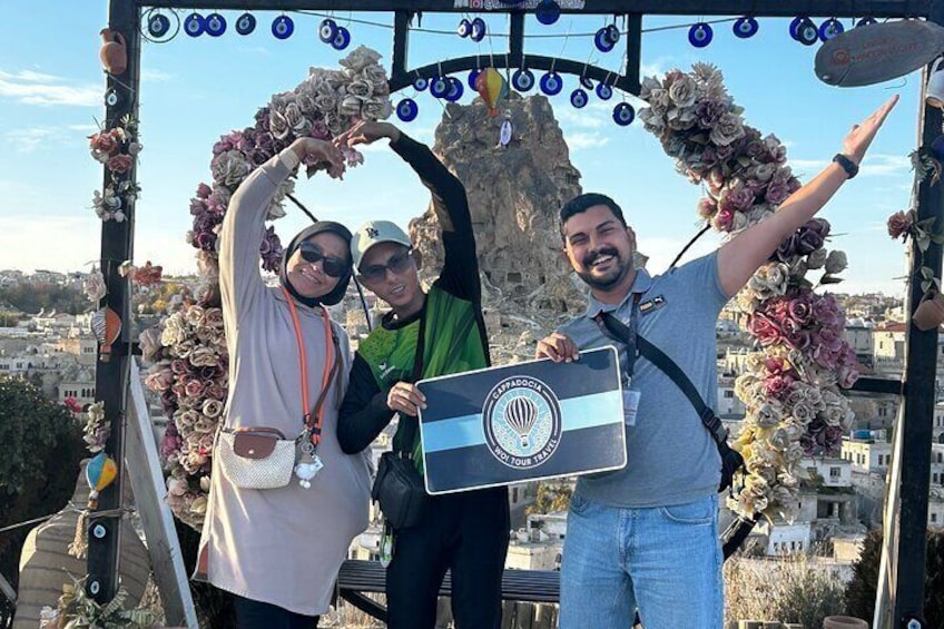 Tres personas posando con un cartel y un arco floral. 1