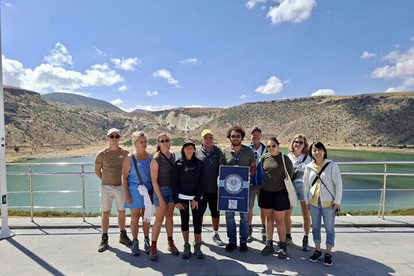 Un grupo de personas en un muelle, con un lago y colinas al fondo. 3