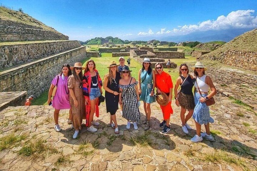 A group of people standing on a stone platform with ancient ruins in the background. 1