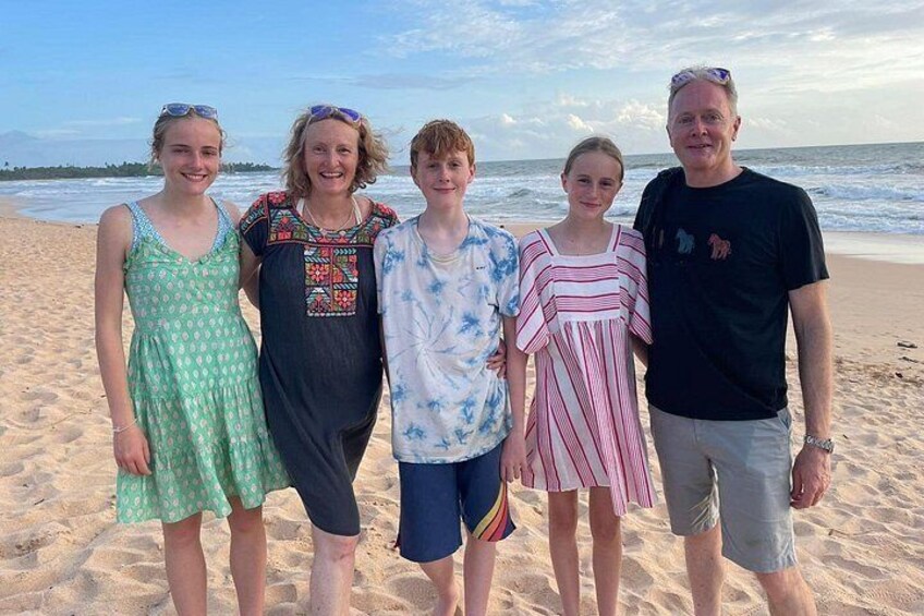 A group of people standing on a sandy beach with the ocean in the background. 3