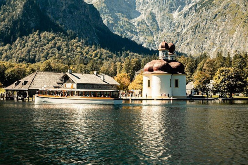 A lake with a boat, a small building with a dome, and mountains in the background. 4