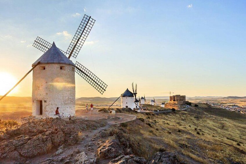 A windmill, a small building, and a distant fortification on a hill. 1