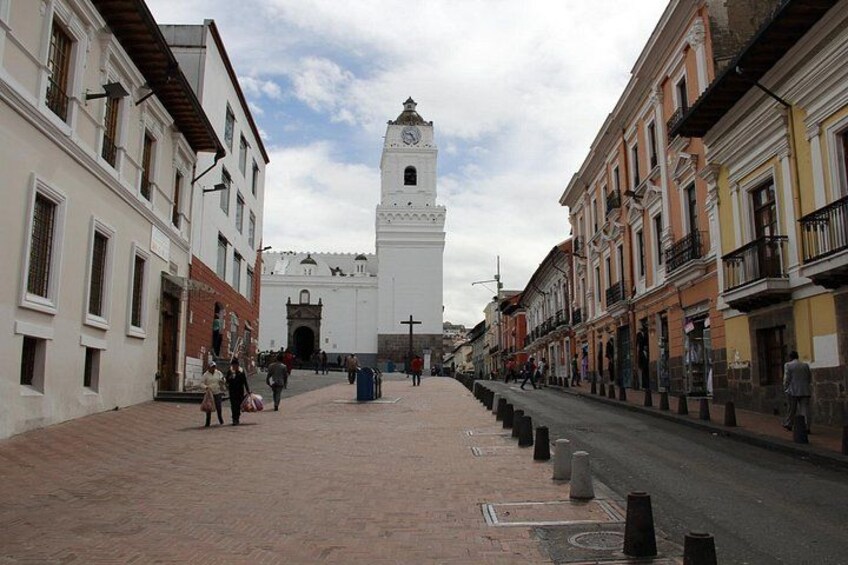 Una calle con edificios, una torre del reloj y defensas antivallas. 2