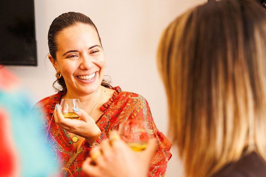 A person holding a glass with a yellow liquid, wearing a red patterned garment. 5