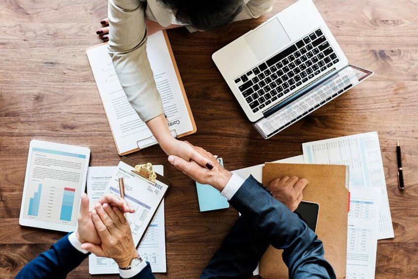 A wooden table with documents, a laptop, and a pen. 5