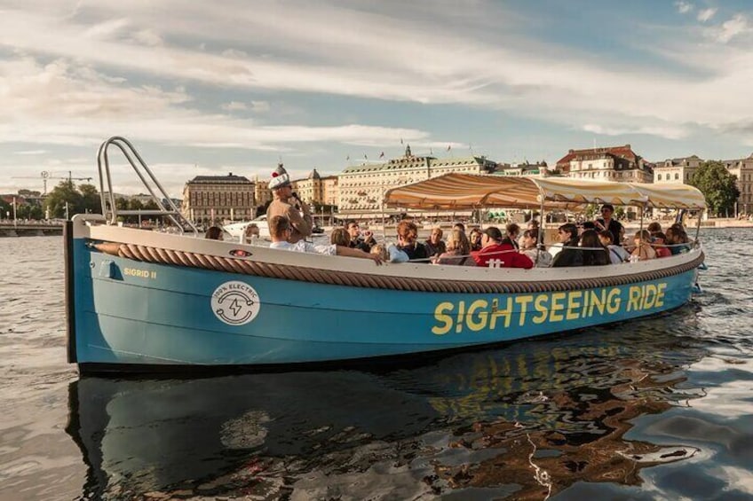 A sightseeing boat with people on board, a cityscape in the background, and a body of water. 3