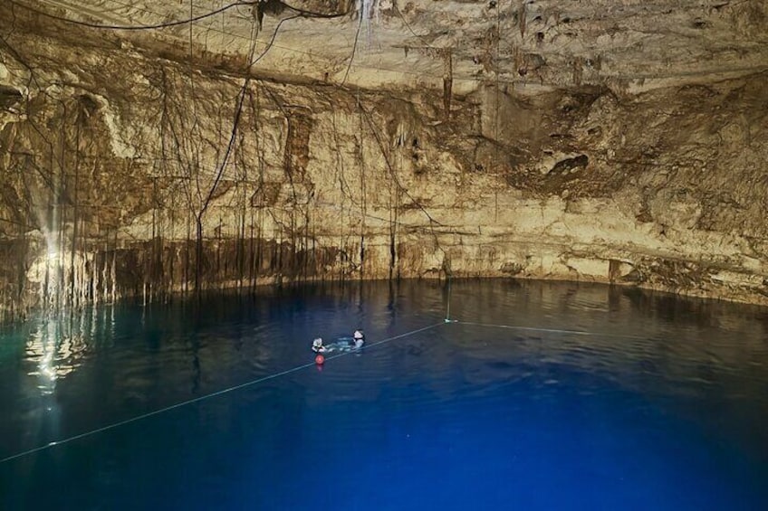 A cave with a blue pool and two people on a rope. 2