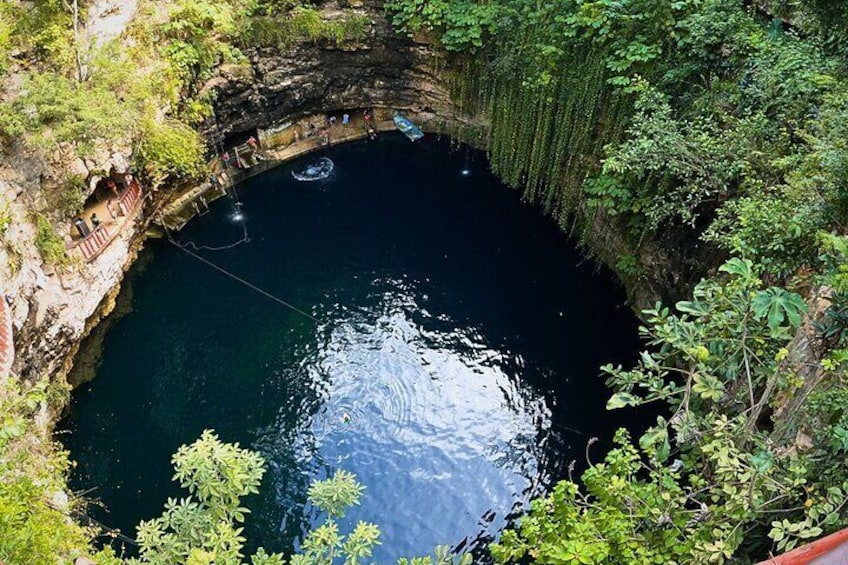 A circular natural pool surrounded by lush greenery and rocky cliffs. 4