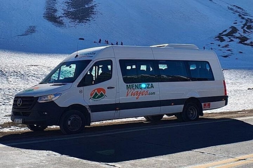Ein weißer Van mit der Aufschrift 'MENDOZA' und 'Vineyard.com' steht an einem verschneiten See. 2